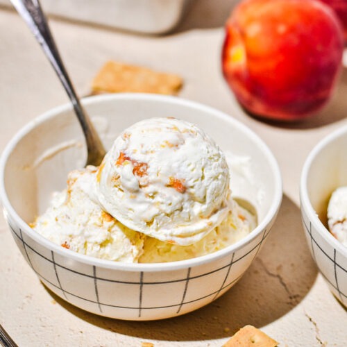Three scoop of peach cobbler ice cream in a bowl with a spoon.