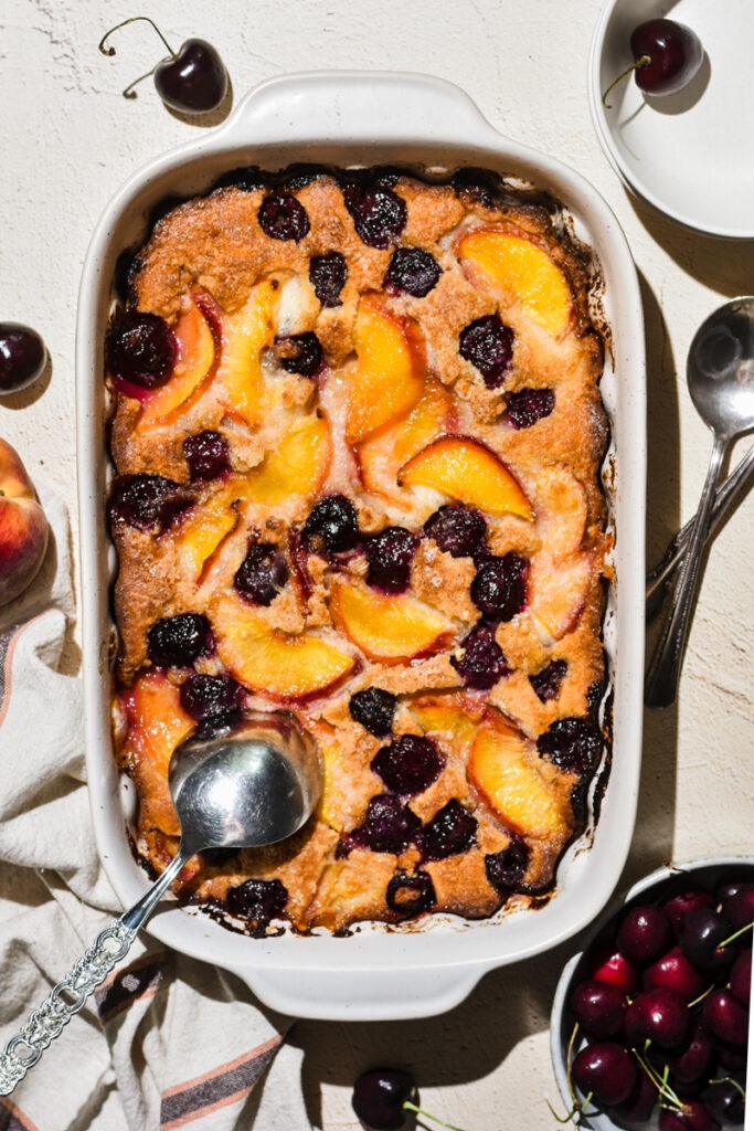Overhead shot of baked peach cobbler in a white baking dish.