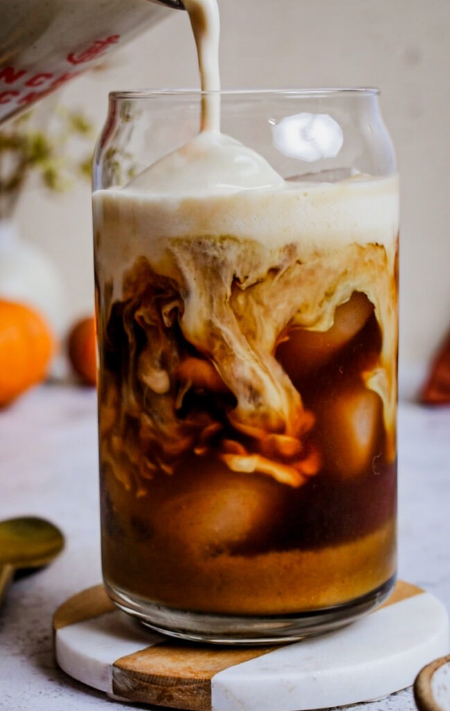Pouring milk into a homemade pumpkin spice latte.