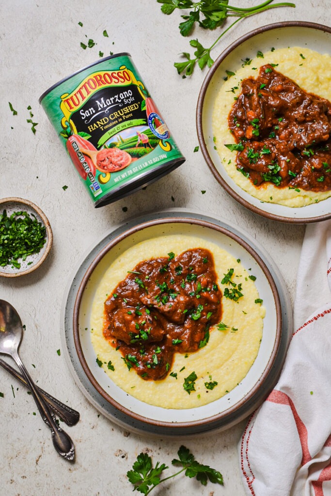 Italian beef stew served with polenta next to a can of crushed tomatoes.