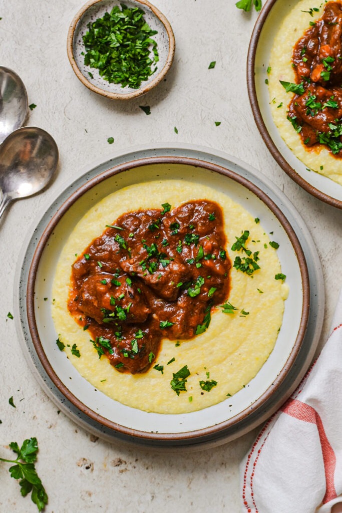 Polenta served with Italian beef stew on top and garnished with parsley.