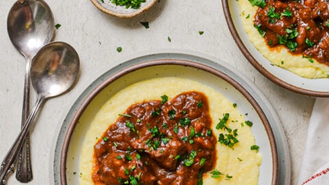Italian beef stew over a bed of polenta in a bowl.