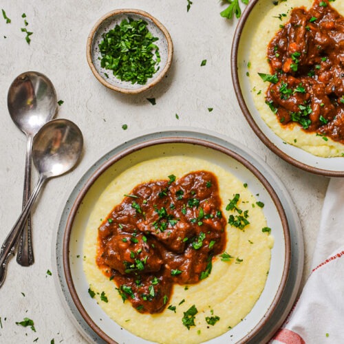 Italian beef stew over a bed of polenta in a bowl.