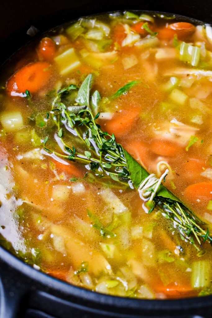 Bouquet garni added to the chicken white bean soup in a pot.