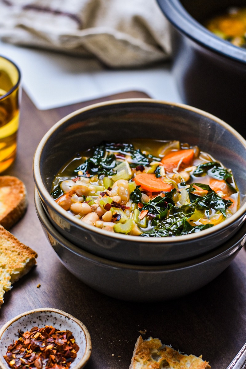 Bowl of chicken white bean and kale soup stacked on another bowl.