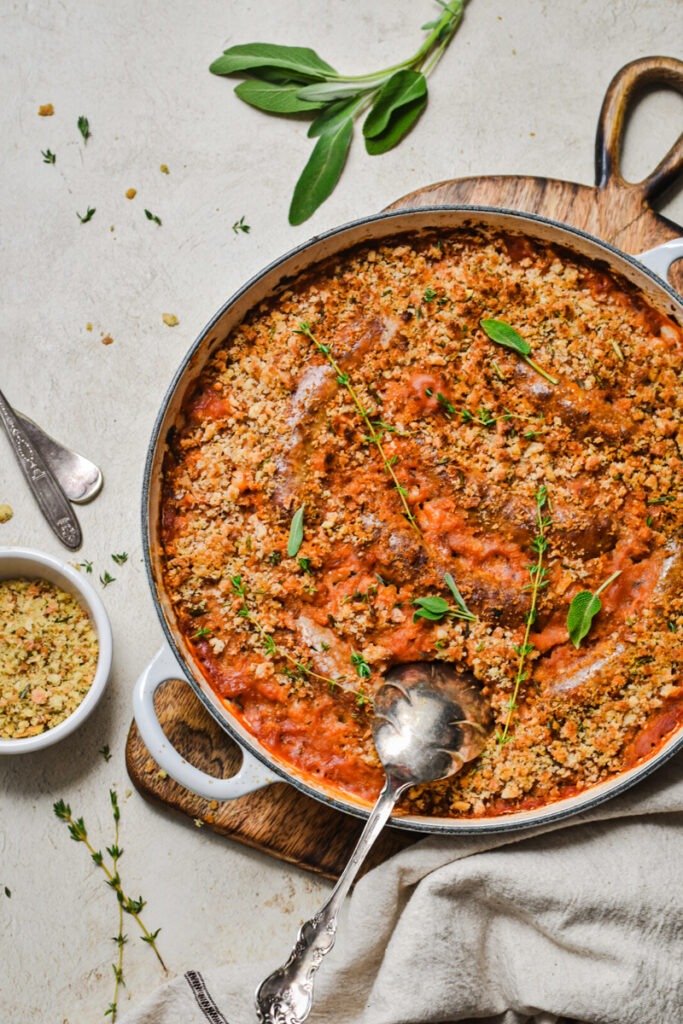 White bean and sausage cassoulet served on a wooden board in a cast iron skillet.
