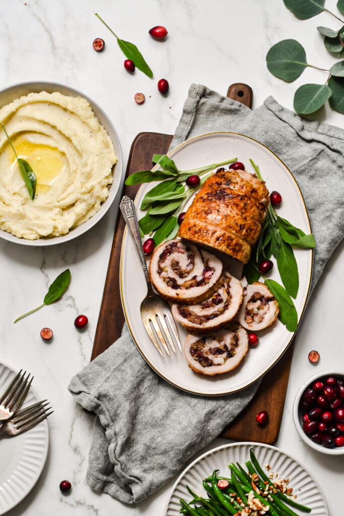 Turkey roulade with apple and cranberry filling on a serving platter.