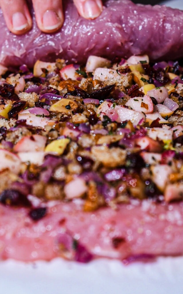 Rolling up the turkey roulade with filling on the inside.