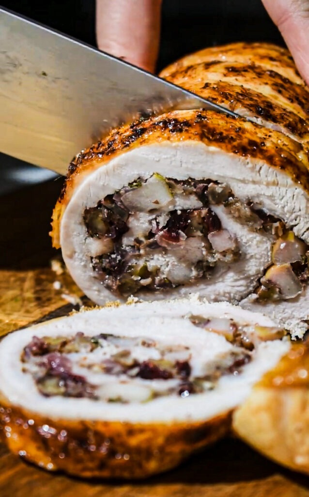 Slicing the apple pecan cranberry turkey roulade with a sharp knife.