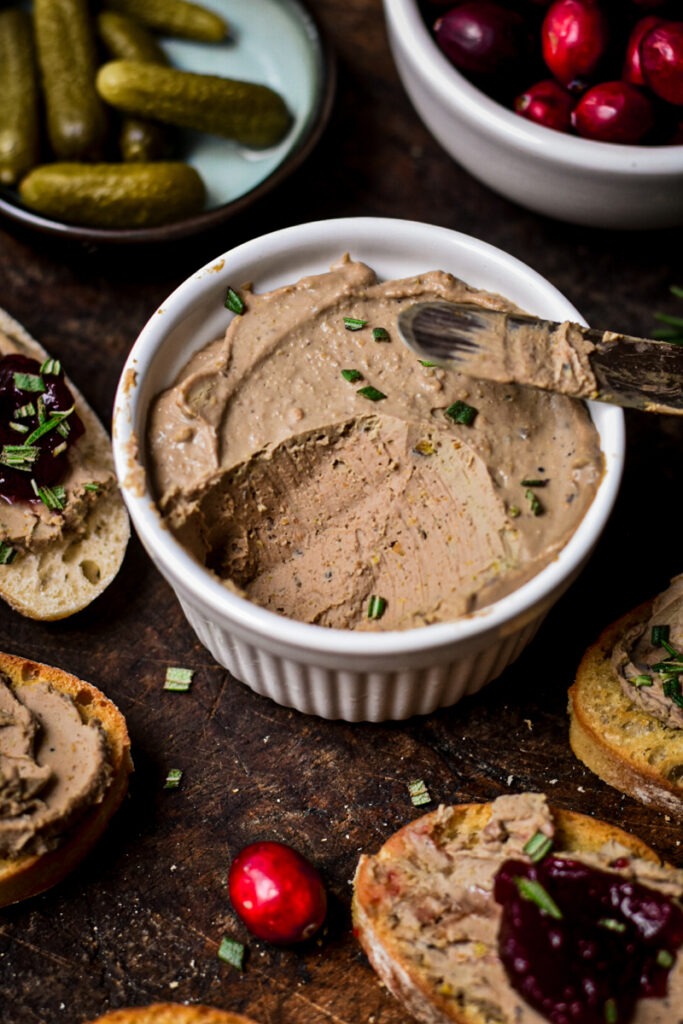 Chicken liver Pâté in a ramekin with some missing from the ramekin.