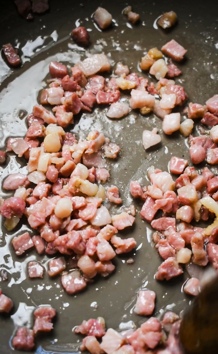 Pancetta being cooked in a pan.