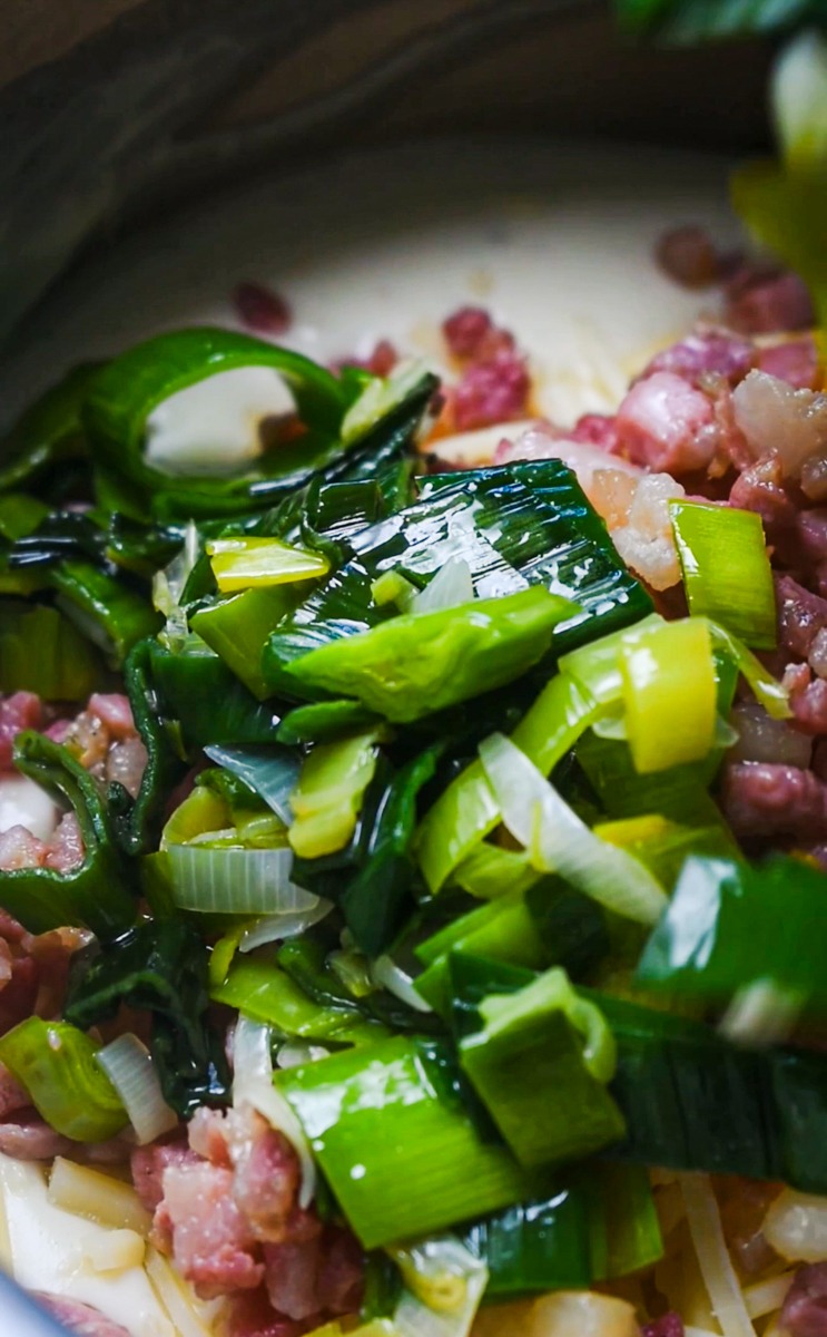Leeks being cooked with the pancetta in a skillet.