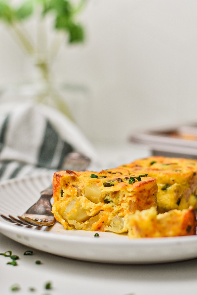 Side view of a potato cheddar chive egg bite on a plate.