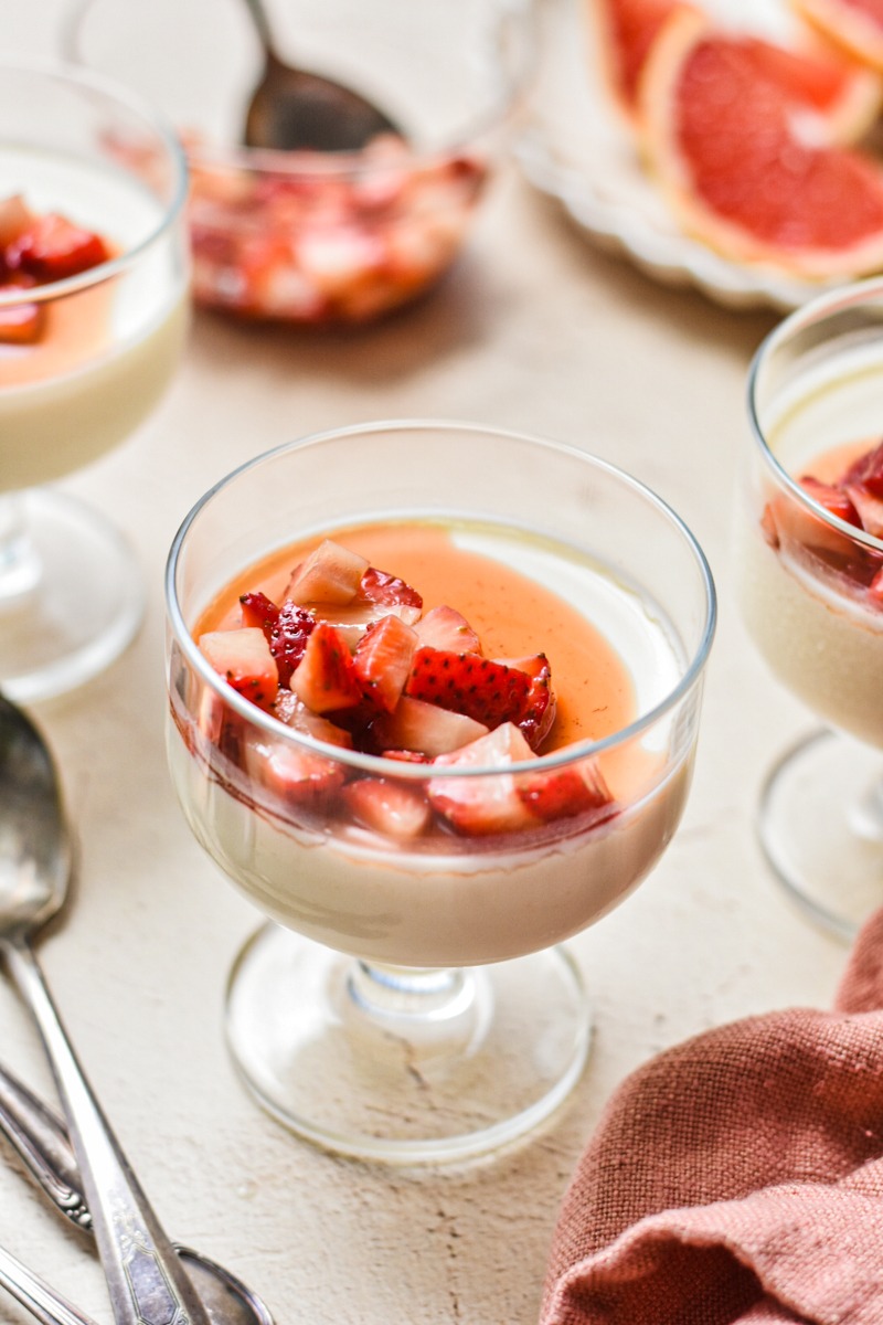 Grapefruit posset in a serving glass with diced strawberries on top.