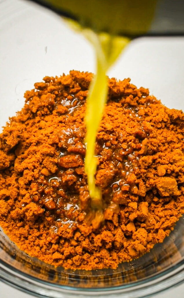 Mixing Biscoff cookie crumbs with melted butter.