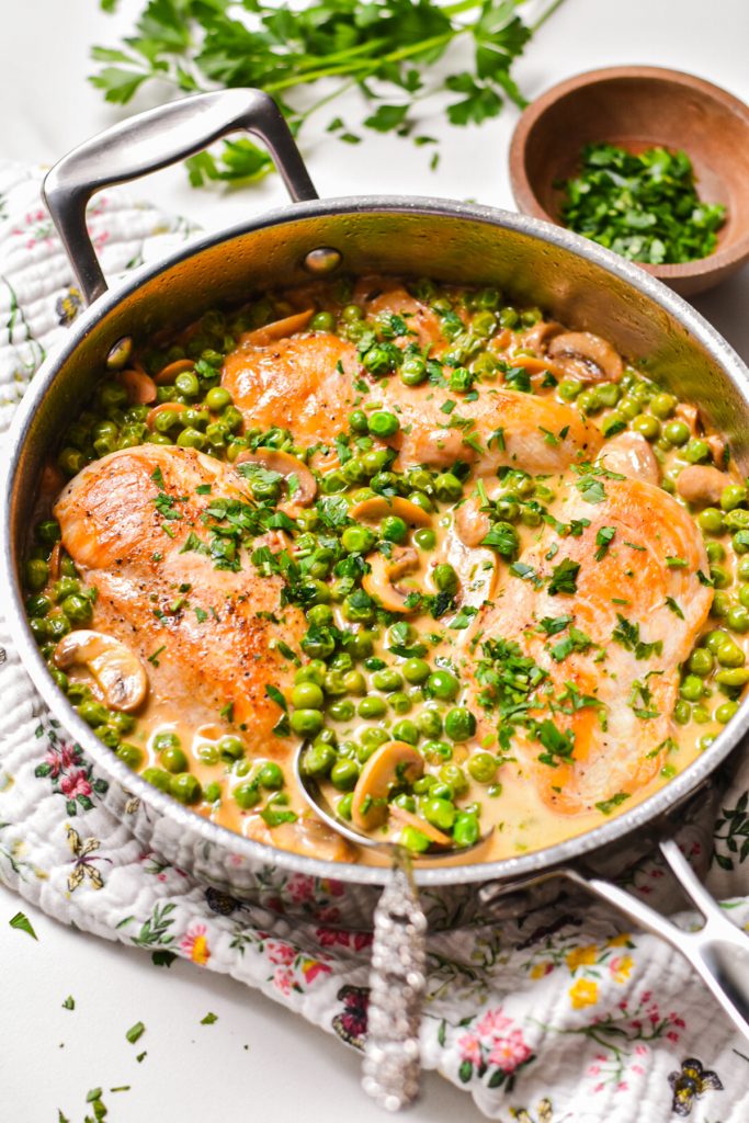pot of creamy mustard chicken with mushrooms and peas topped with parsley
