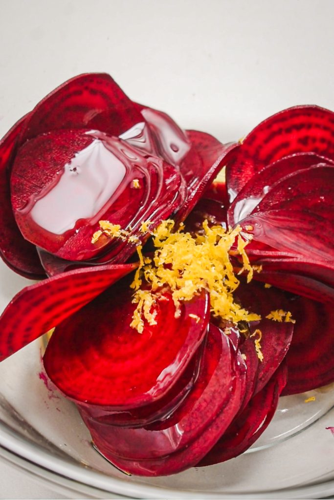 shot of red raw beet slices topped with olive oil and lemon zest