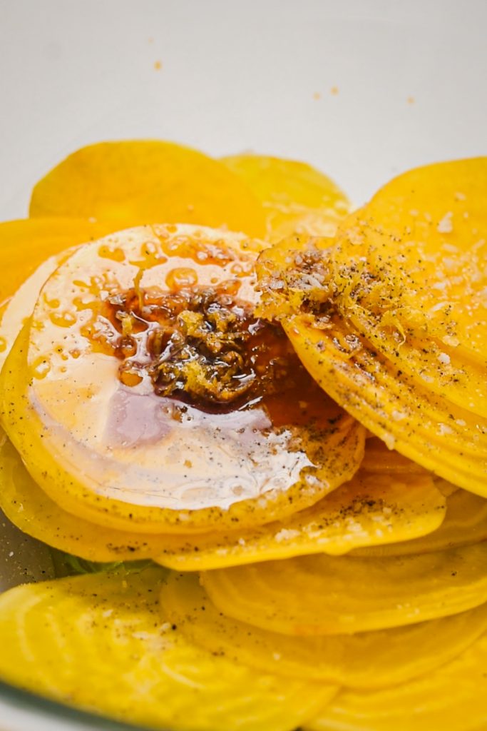 shot of yellow beet slices topped with olive oil and black pepper