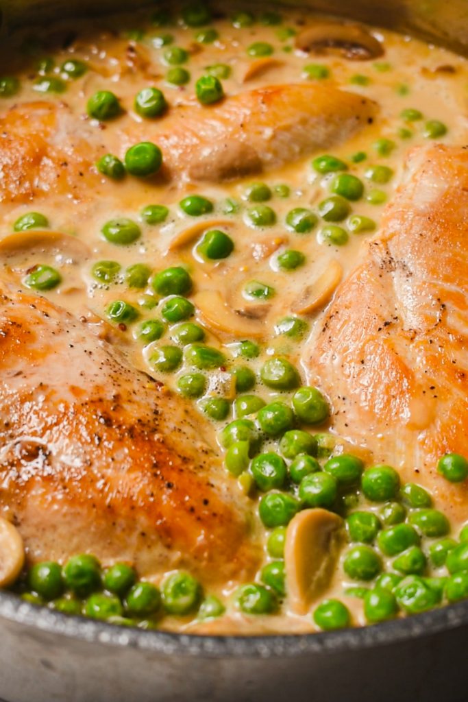shot of appetizing and creamy mustard chicken with mushroom and peas