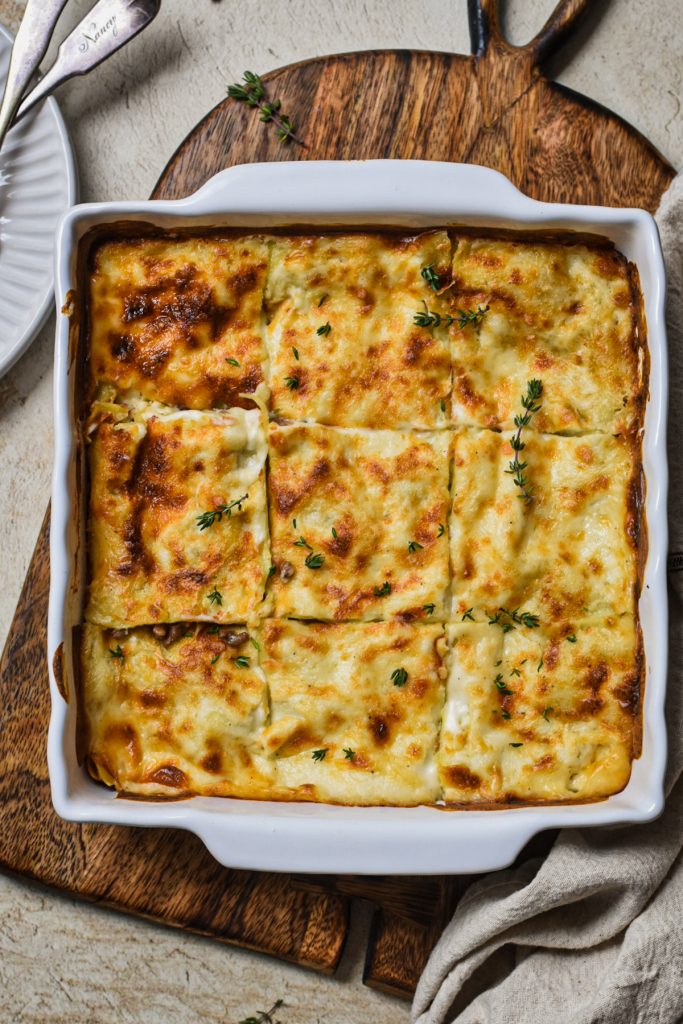 Overhead shot of mushroom and sausage forest lasagna in a white baking dish.