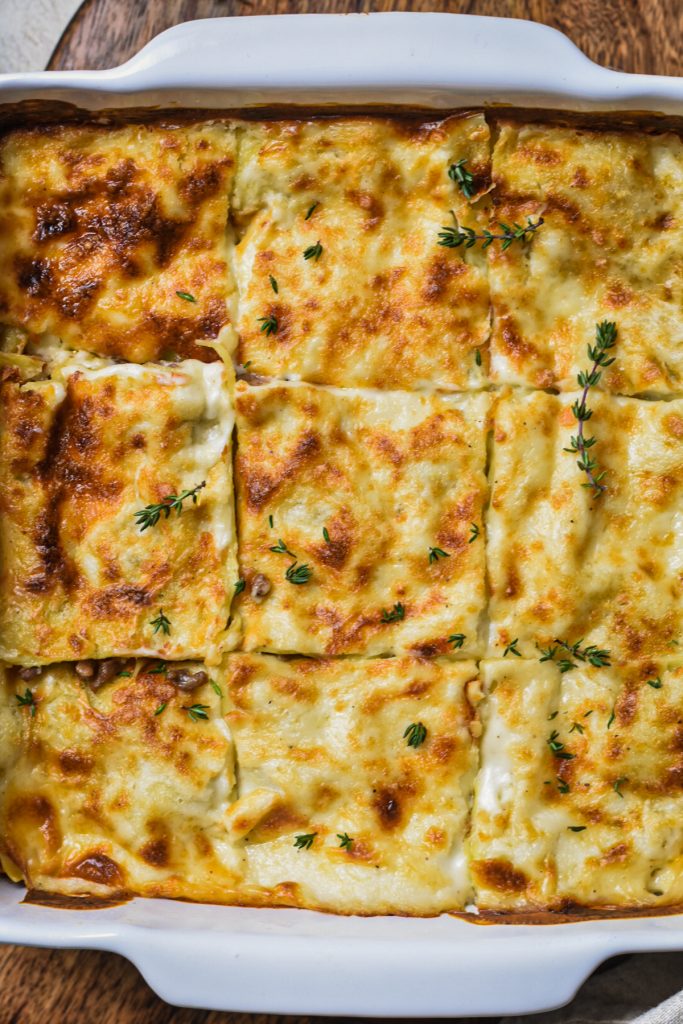 Overhead shot of white lasagna in a baking dish cut into squares.