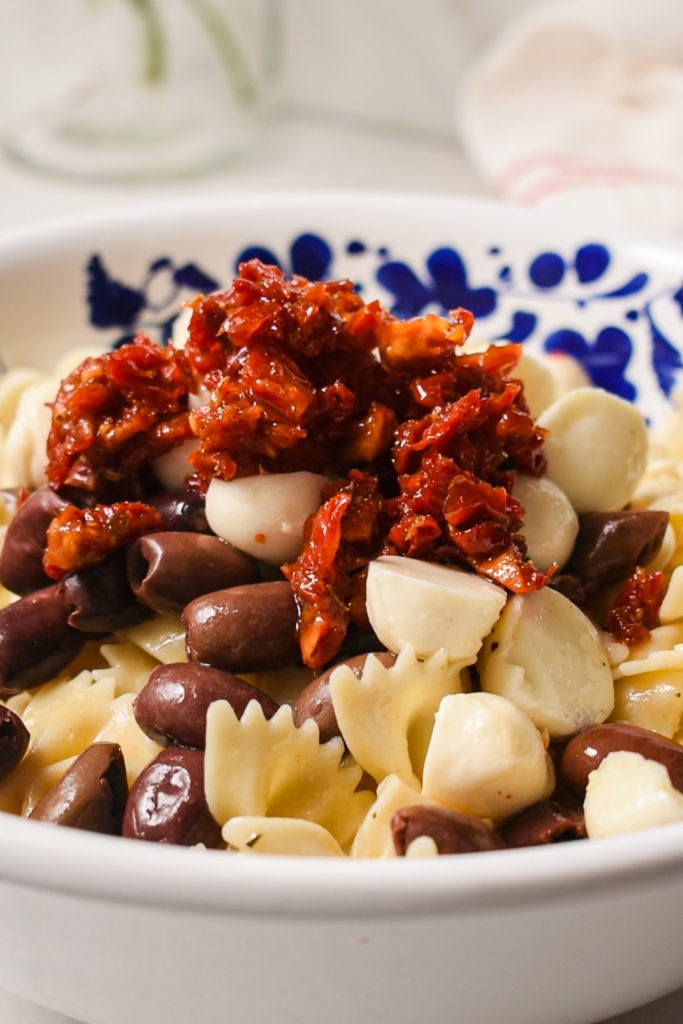 Pasta, olives, mozzarella and sun dried tomatoes in a bowl.