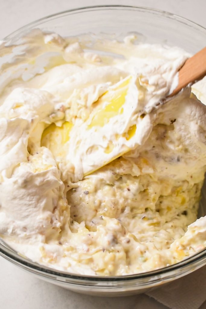 Using a rubber spatula to fold the whipped cream into the rest of the pie mixture.