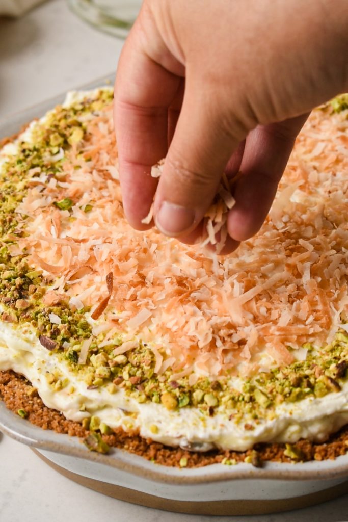 Hand sprinkling toasted coconut on top of the finished million dollar pie.
