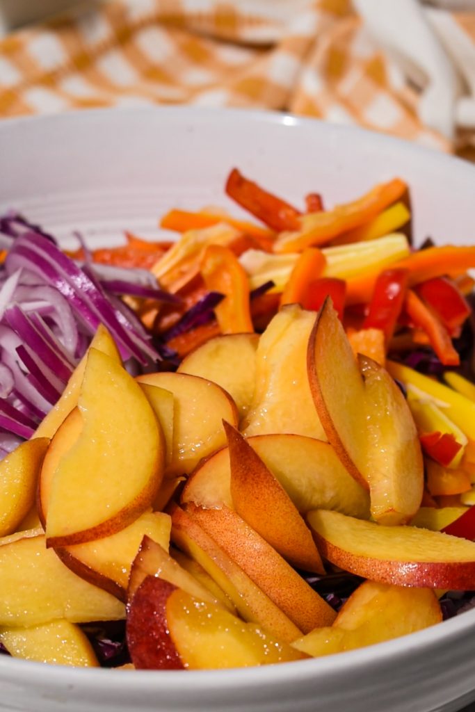 Peaches, peppers, onions and cabbage in a bowl.