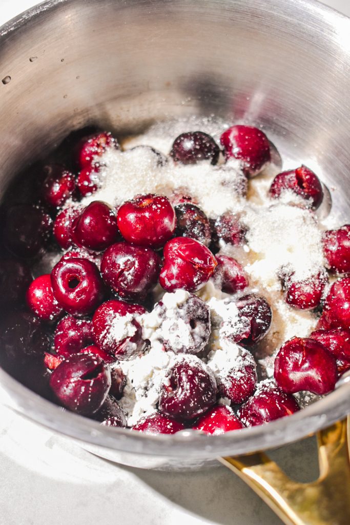 Pitted cherries in a saucepan with sugar.