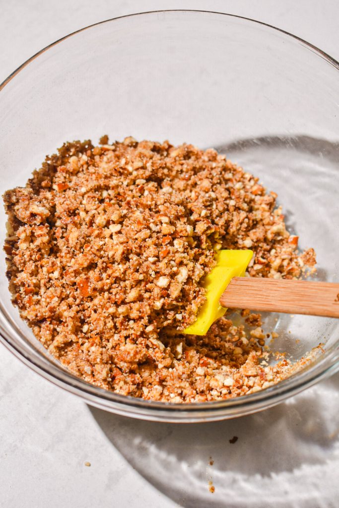 Crushed pretzels being mixed with butter and sugar in a mixing bowl.