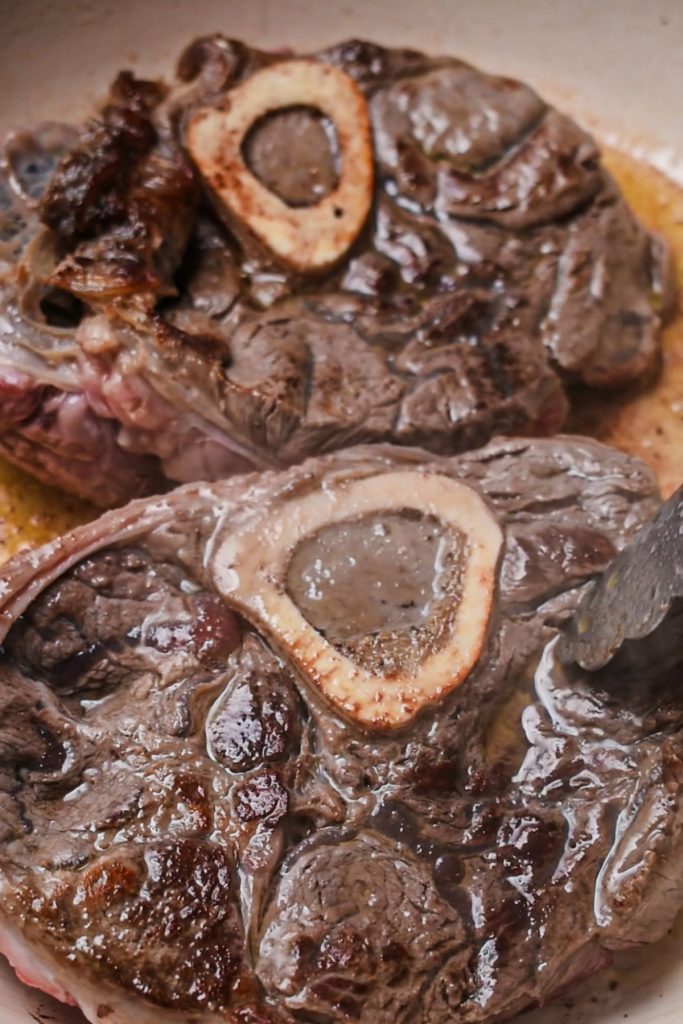 Beef shanks being seared in a Dutch oven.