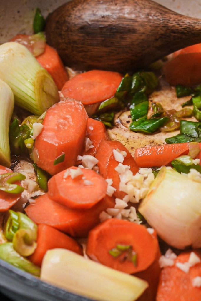 Carrots, onions and garlic being cooked in the pot.