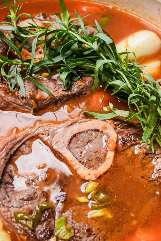 Water and herbs being added to the pot along with the meat.