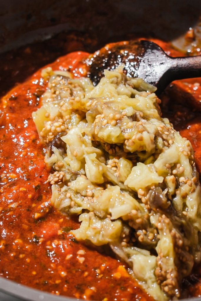 Eggplant added into the tomato mixture in the skillet.