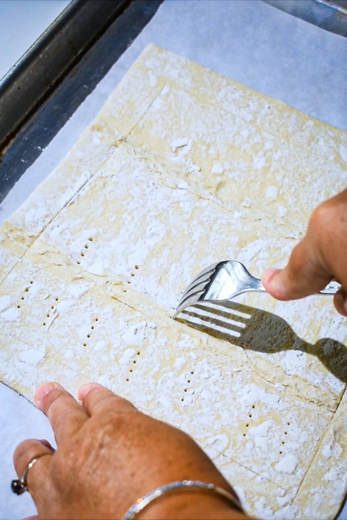 Using a fork to score the puff pastry.
