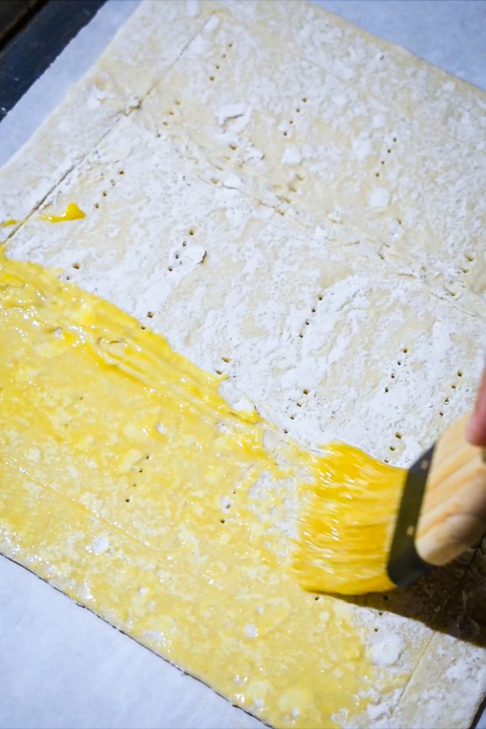 Brushing and egg wash onto the puff pastry sheet.