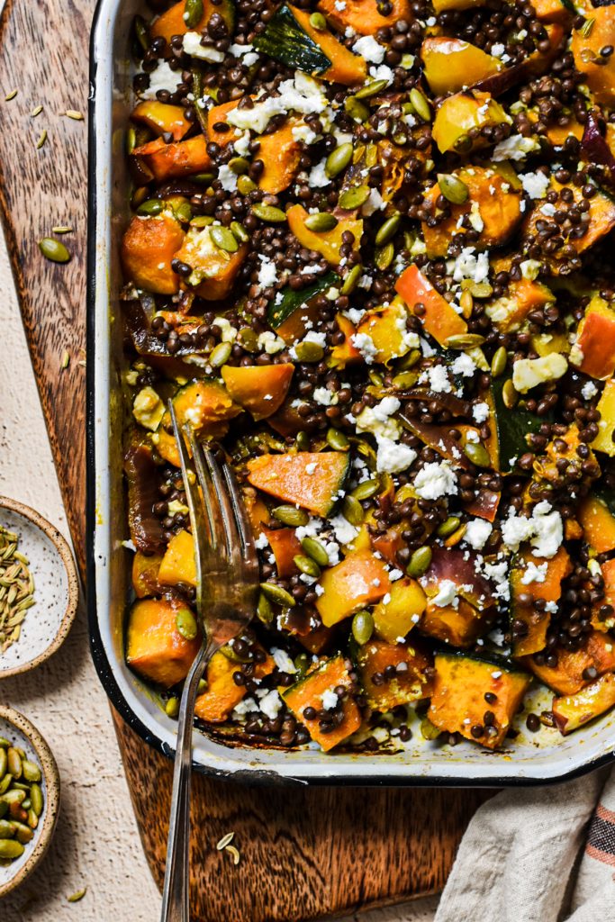 Up close shot of the roasted squash and lentil salad in a baking dish with a large serving fork.