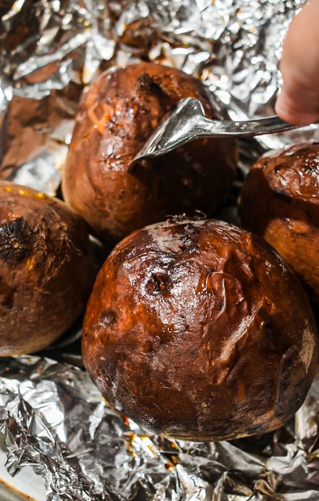 Roasted beets in foil with a fork checking them for doneness.