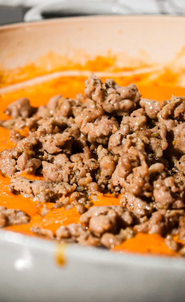 Adding the browned Italian sausage back into the skillet with the sauce.