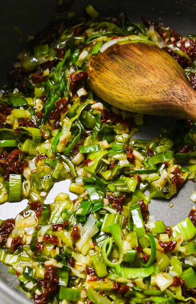 Leeks and sun dried tomatoes sautéing in a large stock pot.