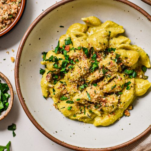 Beer cheese poblano macaroni and cheese served in a bowl and topped with parsley and toasted breadcrumbs.