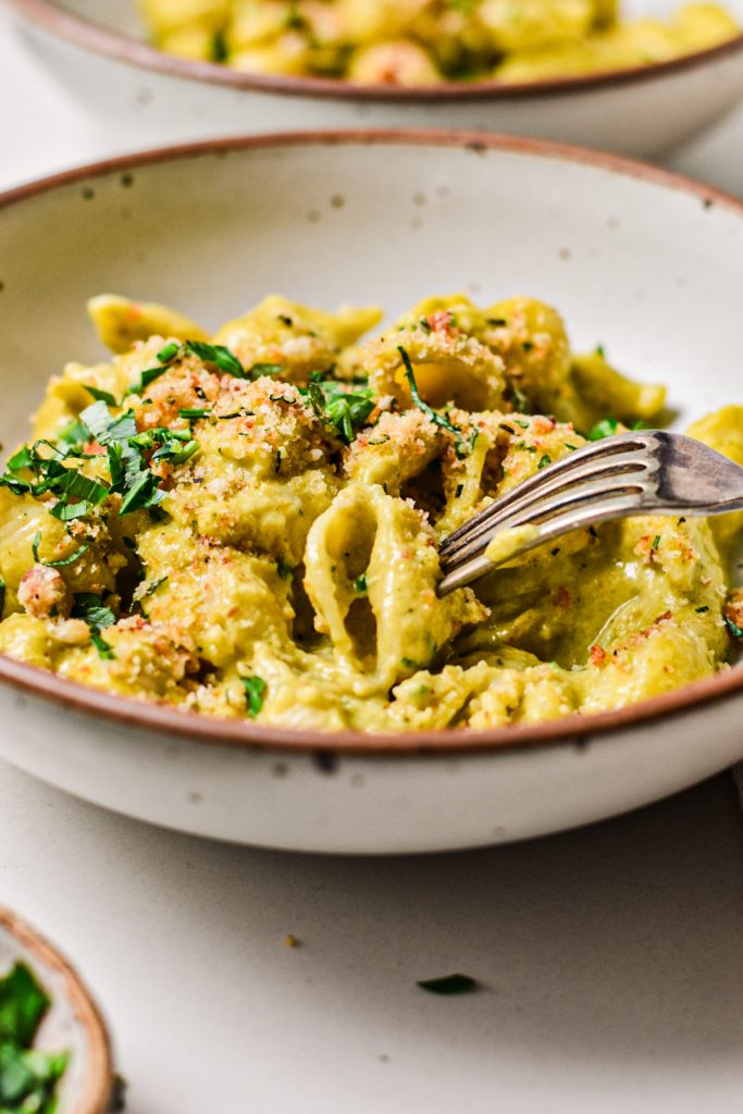 Fork taking a bite from a bowl of beer cheese poblano mac and cheese.