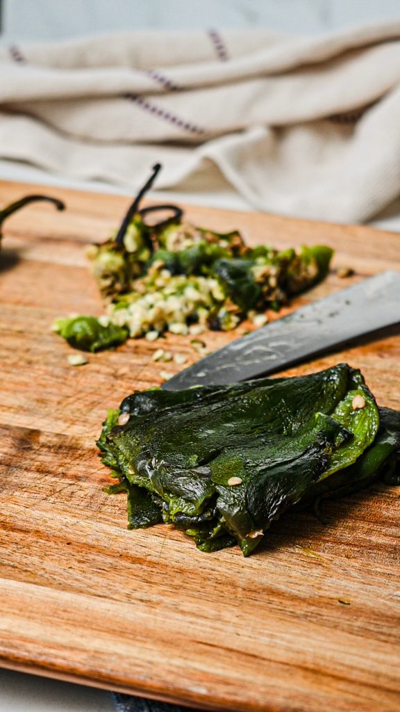 Roasted poblano and jalapeno peppers with the skins and seeds removed on a cutting board.