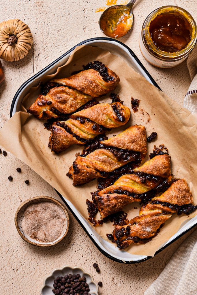 Overhead shot of pumpkin butter and chocolate chip twists on a small baking sheet lined with parchment paper.