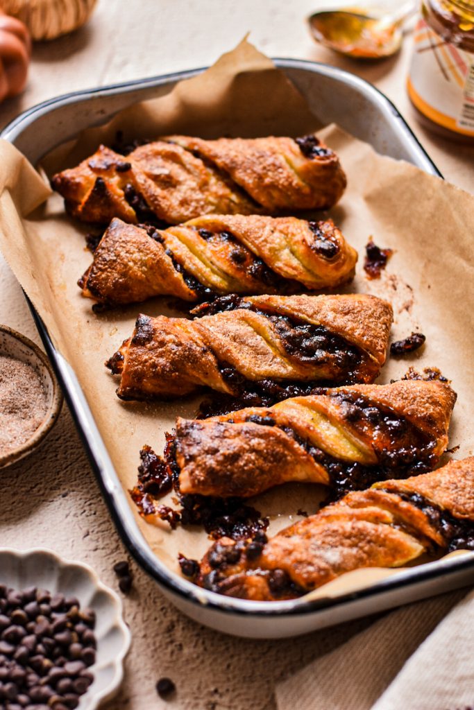 Crispy pumpkin butter and chocolate chip twists on a baking sheet lined with parchment paper.