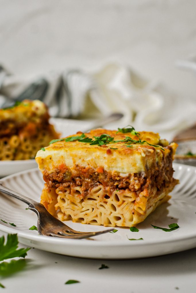 Slice of Greek pastitsio on a plate from the side to show the layers.