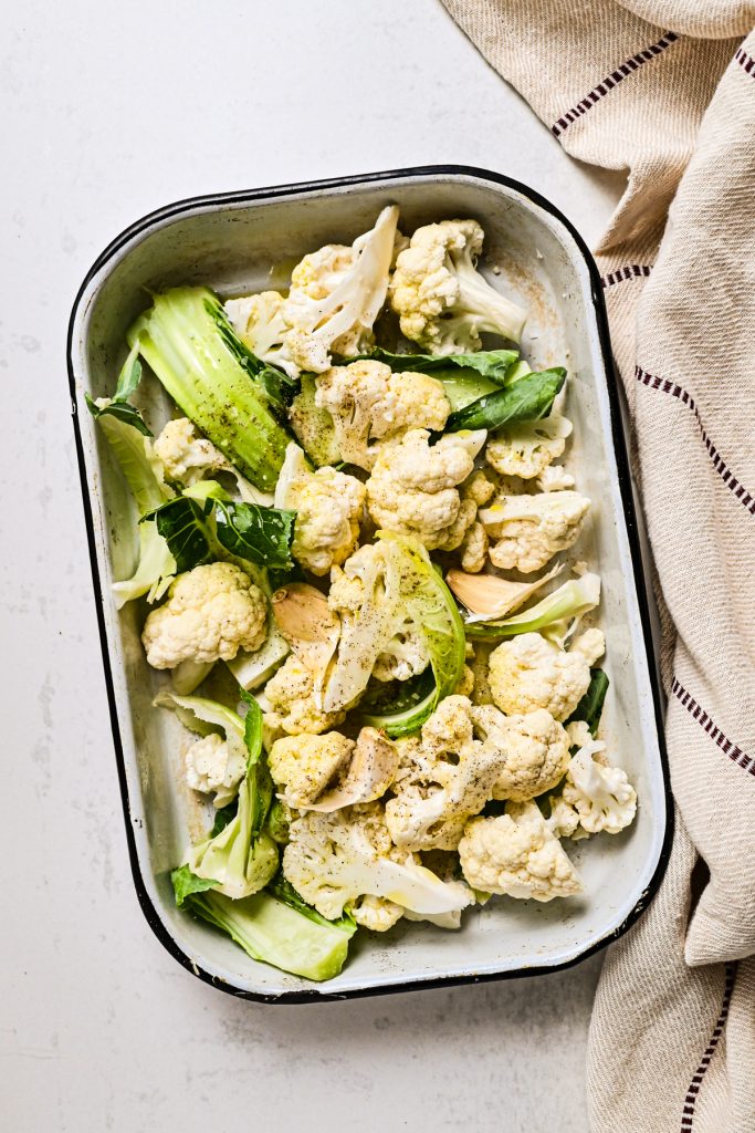 Cauliflower florets with salt and pepper in a baking dish.