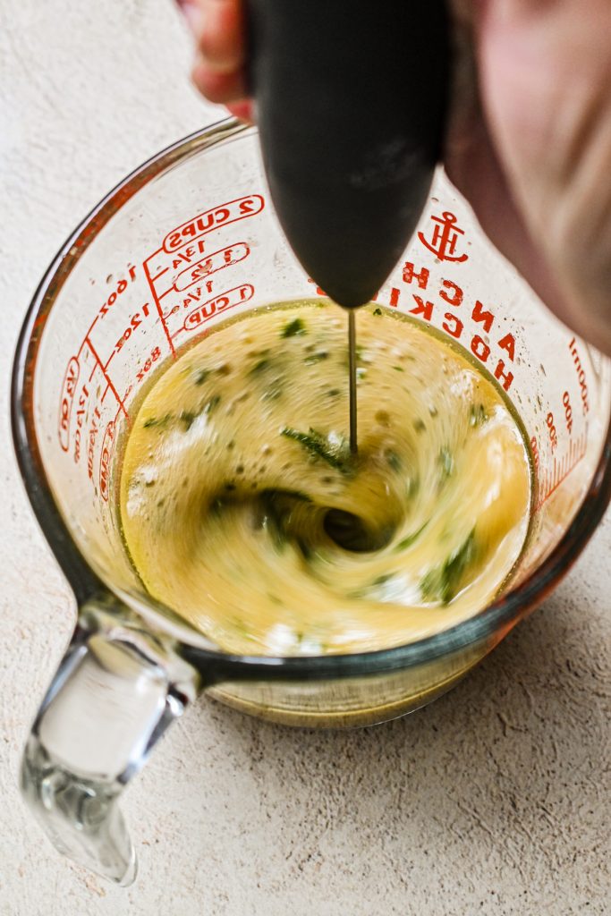 Using a milk foamer to gently combine the marinade for the turkey breast.