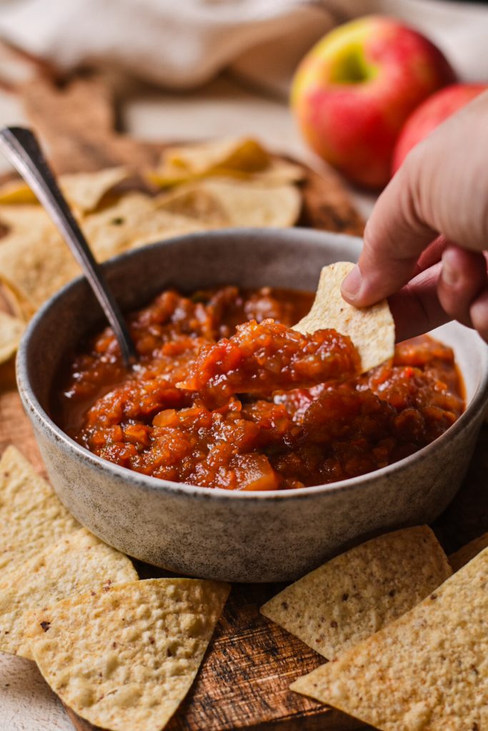 Dipping a chip in the Southern apple salsa from a serving bowl.